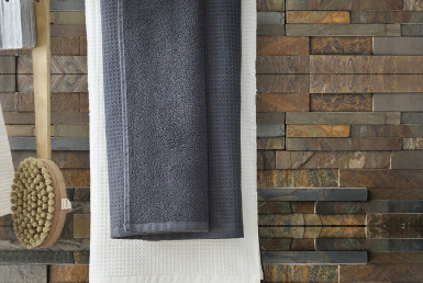 baño espacio interior ducha con piedra natural tonos tierra cepillo y toalla