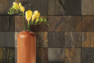 pared de piedra natural tonos tierra florero naranja y flores amarillas