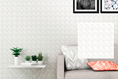 Cerámica decorativa blanca en pared de dormitorio, con sillon gris y adormos flores decorativas.