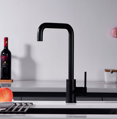 Griferia negro mate para cocina de calidad, con meson blanco una botella de fondo con pared de porcelanato blanco puro