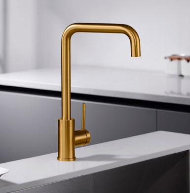 Grifo para cocina dorada elegante y moderno con meson blanco puro y pared blanca