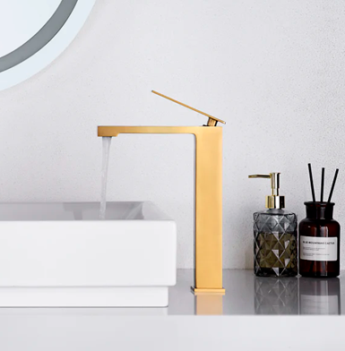 PISA ORO CEPILLADO ALTA Grifo alto dorado con lavamanos blanco moderno Quito y mesón con pared de piedra sinterizada blanco.