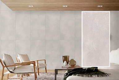 Rivera-blanco-porcelanato-pared Porcelanato en pared tipo cemento color gris, con asiento blanco y mesa de centro decorativa.